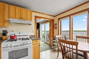 A kitchen with a stove, cabinets, and a view of the water.