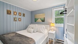 A bedroom with a bed, a nightstand, a window, and wall decorations.