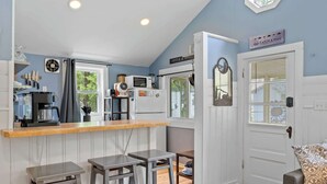 A compact kitchen with a bar area, a dining space, and a door with a sign.