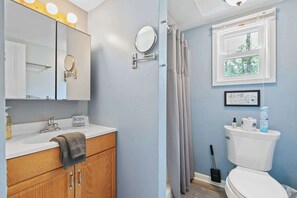 A bathroom with a sink, mirror, towel, toilet, and window. - Blue Sky Cottage: Sunset Shores Kangaroo Lake (Baileys Harbor)