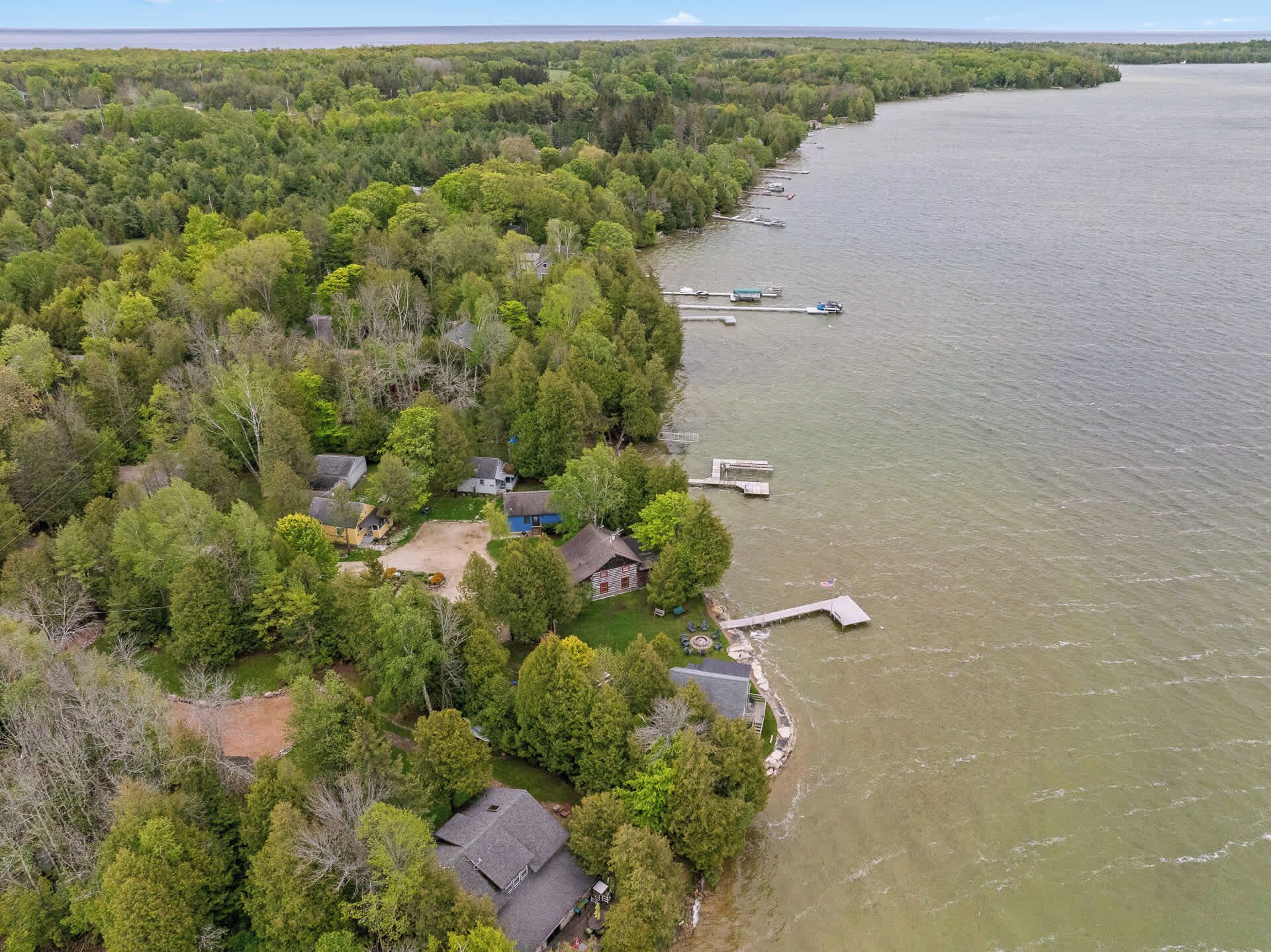Vue aérienne d’une propriété au bord du lac, avec plusieurs maisons, des quais et un bateau amarré.