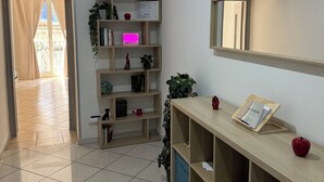 A well-lit room with a tiled floor, a wooden bookshelf, a mirror, and a door leading to a balcony. - Andrea's Place - cozy apartment 5 minutes from the Archaeological Museum (Napoli)