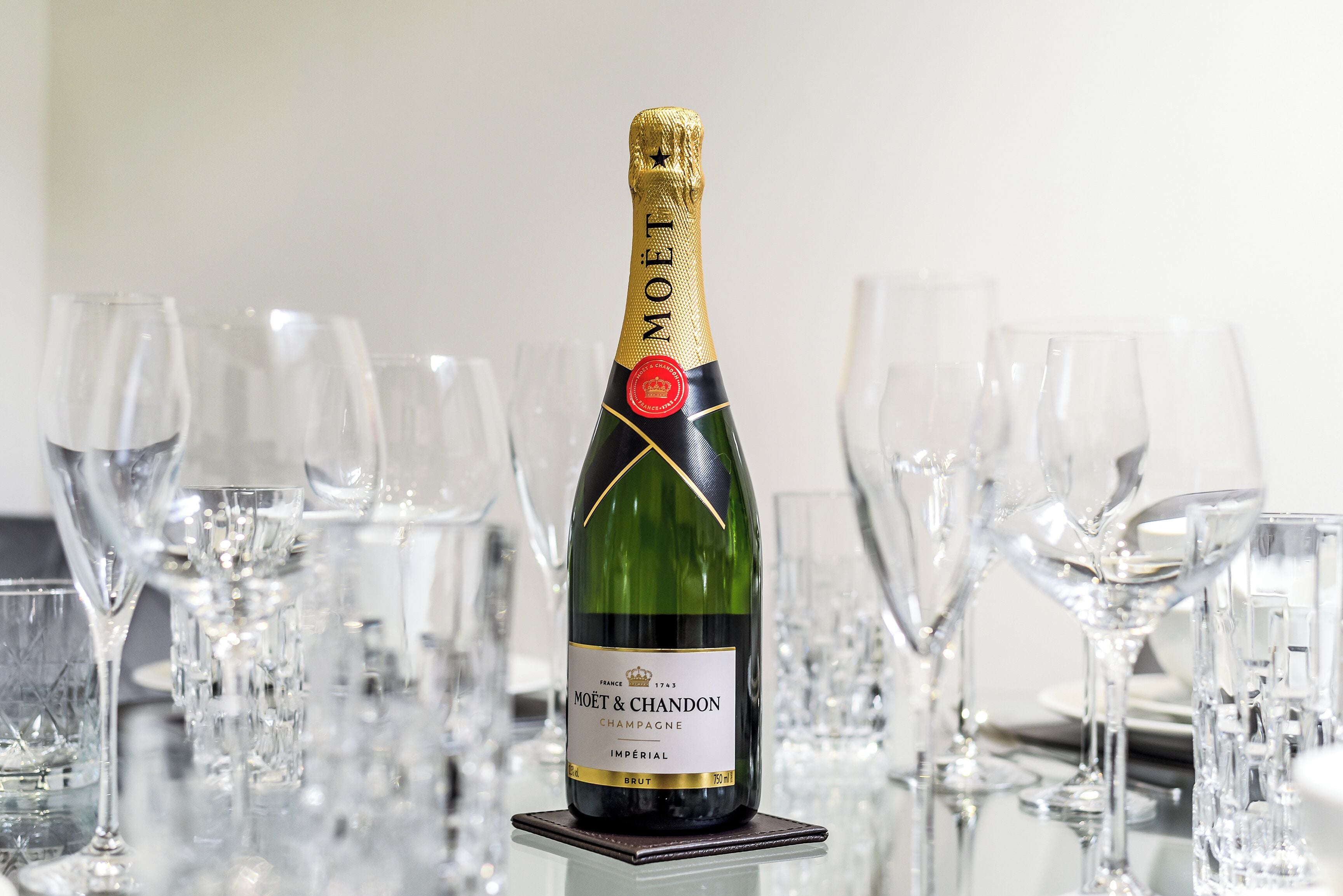 Une bouteille de champagne Moët & Chandon sur une table, entourée de verres à vin vides.