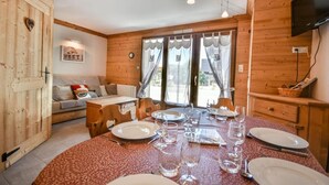 A wooden interior with a dining table set for four, a sofa, and a TV mounted on the wall. - Ground floor, parking, ski locker, 45m², Les Gets (Les Gets)