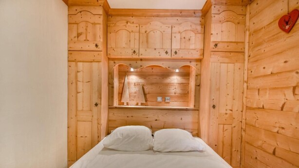 A wooden room with a bed, a shelf with decorative items, and a heart-shaped decoration on the wall. - Ground floor, parking, ski locker, 45m², Les Gets (Les Gets)