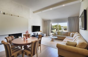 Relax in this stylish living room with a round dining table, comfortable sofa, and flat-screen TV.