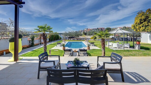 Eine Terrasse mit Gartenmöbeln, einem Swimmingpool und Blick auf die Nachbarschaft.