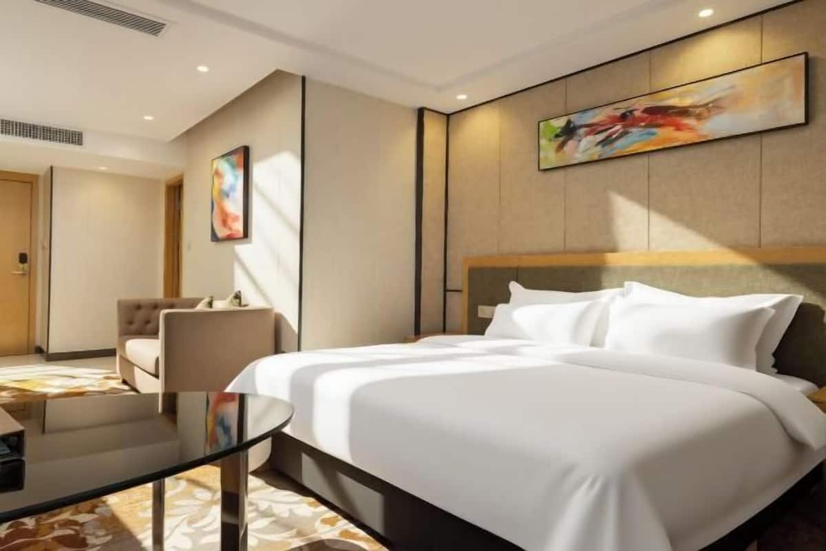 Une chambre d’hôtel avec un lit, une chaise, une table en verre et un tableau au mur.