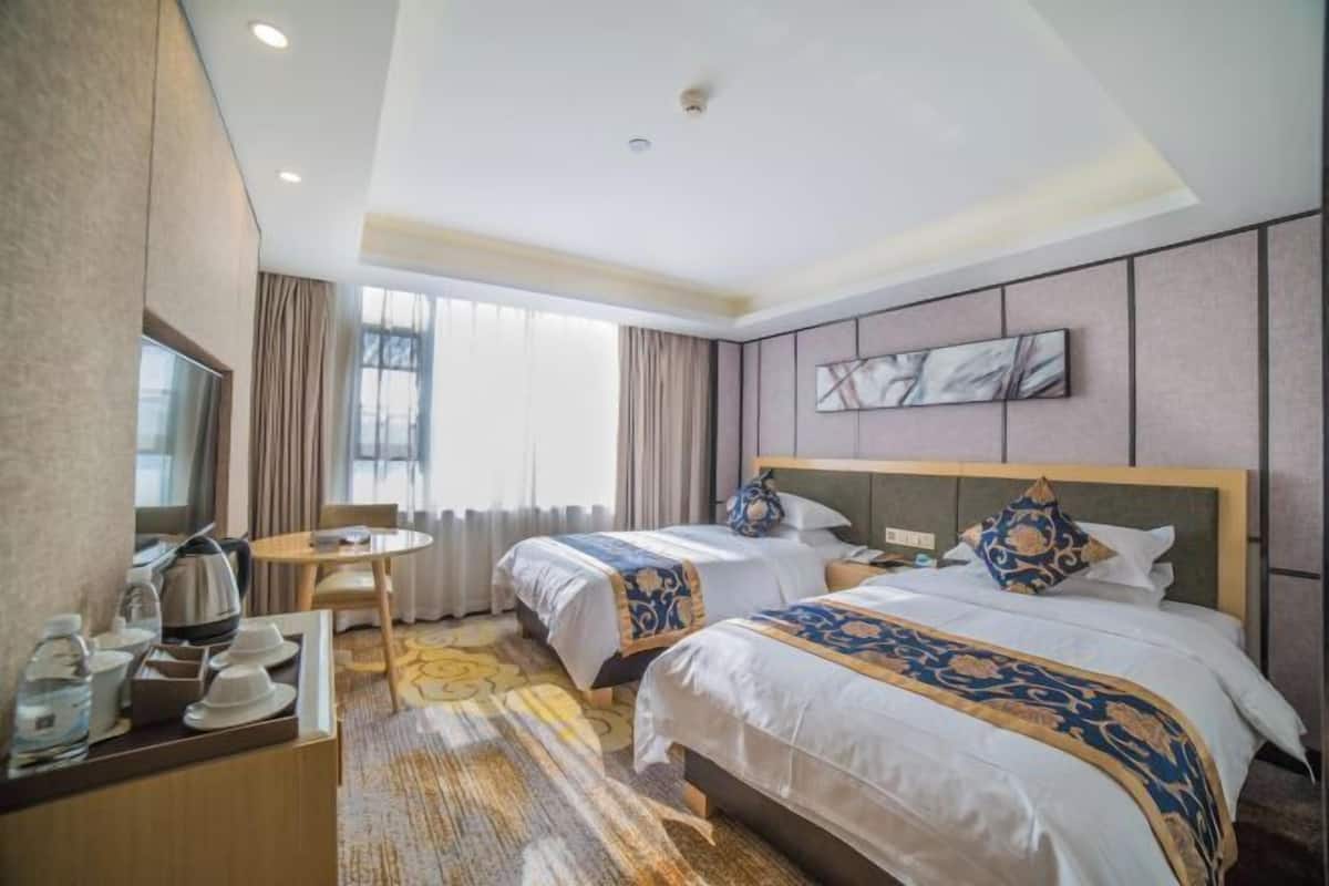 Une chambre d’hôtel avec deux lits, une table à manger, une machine à café et une grande fenêtre.