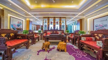 A traditional-style lobby with wooden furniture, a patterned carpet, and a central seating area.