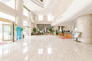 A spacious lobby with a reception desk, a large plant, and a marble floor. - Jiulong International Hotel (Wuhan Yellow Crane TowerRailway Station) (Wuhan)