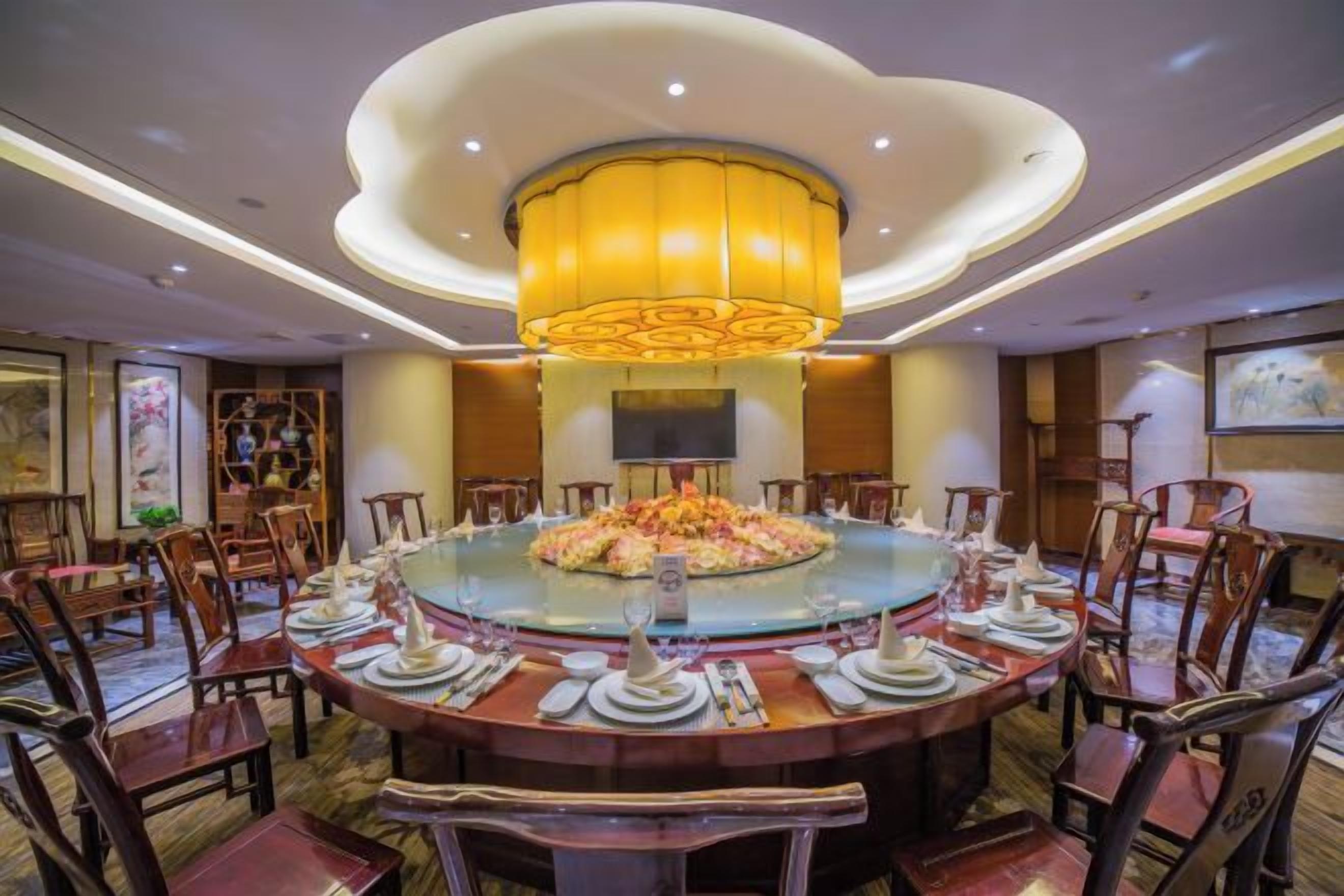 A round dining table with chairs, a central decorative piece, and a modern chandelier.