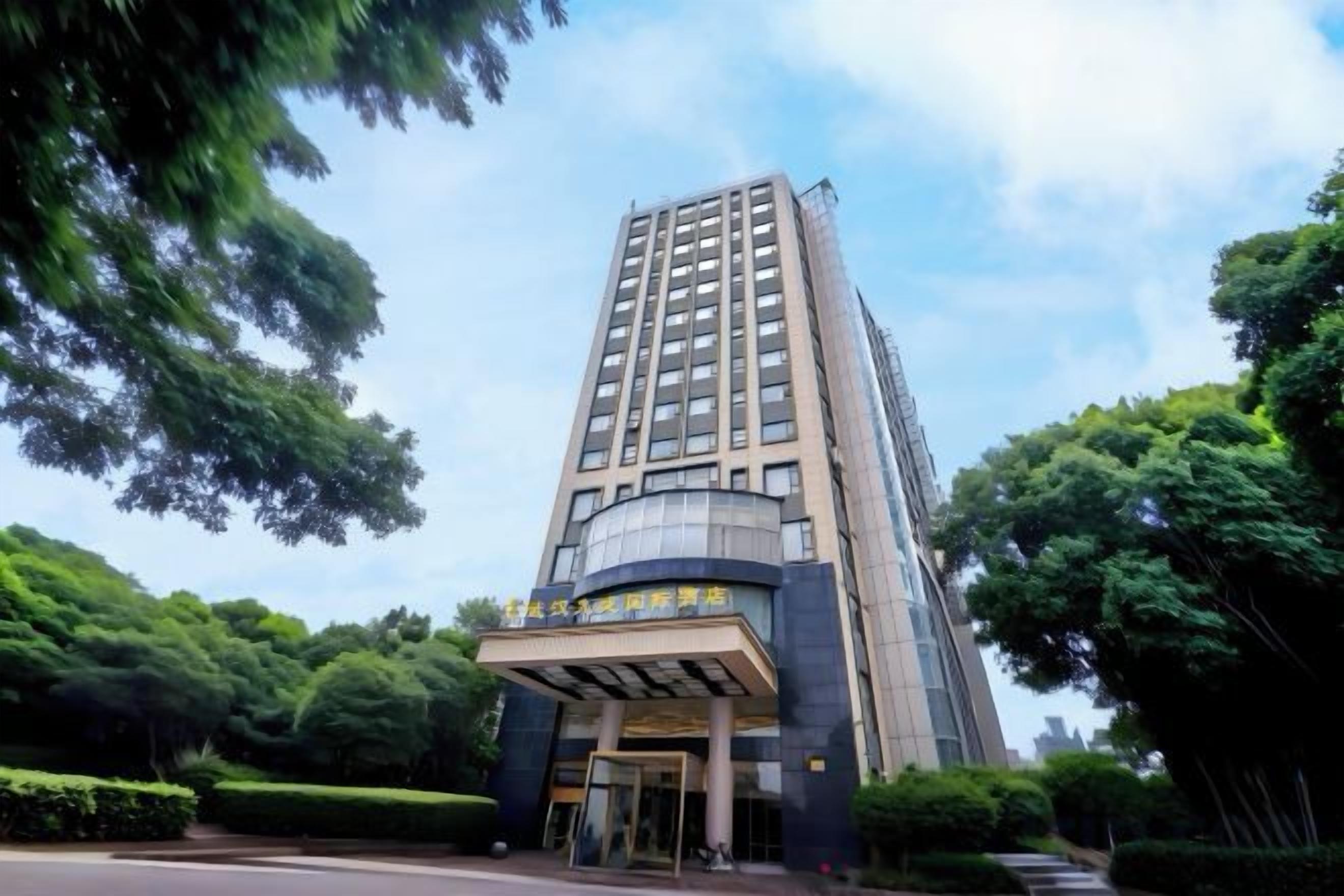 A tall hotel building with a modern facade, a prominent entrance, and a clear sky.