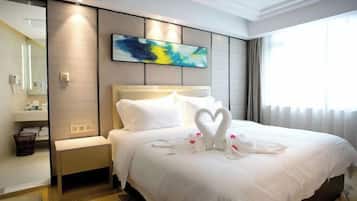 A hotel room with a large bed, a bedside table, a nightstand, a mirror, and a window with curtains.