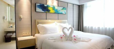 Habitación de hotel con una cama grande, una mesita de noche, un espejo y un ventanal con cortinas.