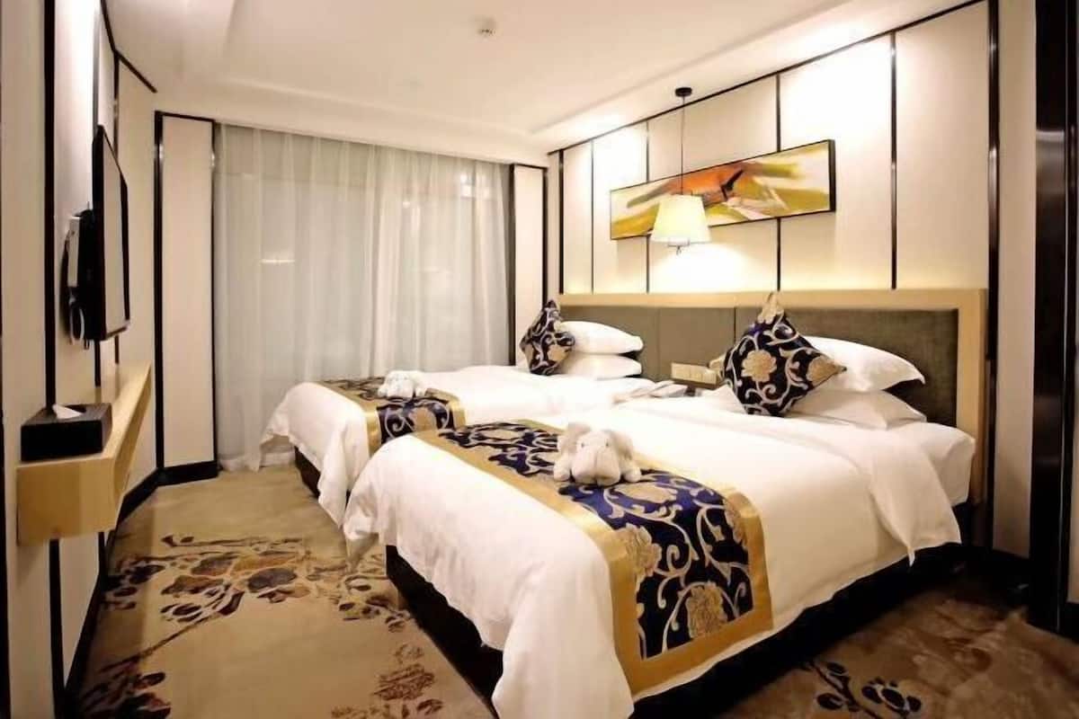 Une chambre d’hôtel avec deux lits, une télévision, une lampe et un tableau au mur.