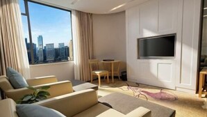 Une chambre d’hôtel moderne avec vue sur la ville, une télévision à écran plat, un coin repas et un canapé.