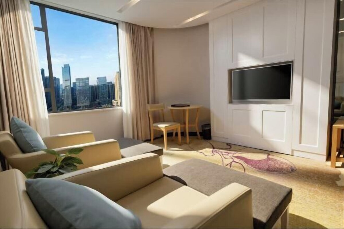 Una habitación de hotel moderna con vista a la ciudad, televisión de pantalla plana, zona de comedor y sofá.
