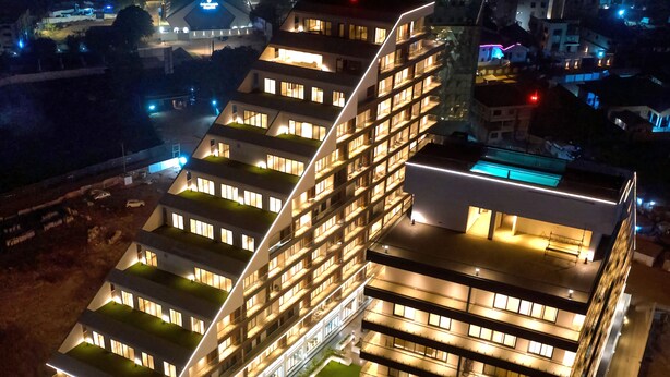 A modern hotel with multiple floors, a rooftop pool, and well-lit balconies.