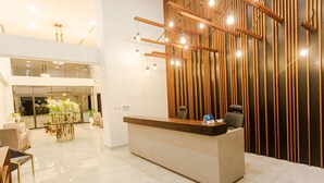 A modern reception area with a wooden reception desk, a glass partition, and a seating area with chairs and a table.