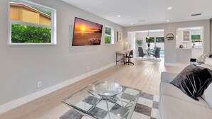 A spacious living area with a glass coffee table, a sofa, and a dining area with a table and chairs.