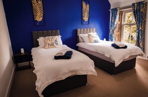 Una habitación de hotel con dos camas, una mesita de noche y una ventana con cortinas.