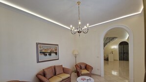 A spacious living room with a sofa set, a coffee table, and a chandelier. - Villa Esmeralda (Salerno)