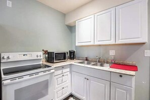 Een magnetron, een oven, een kookplaat, kookgerei, borden en bestek