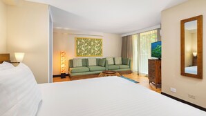 Ein Hotelzimmer mit einem großen Bett, einer Couch, einem Fernseher und einem Spiegel.