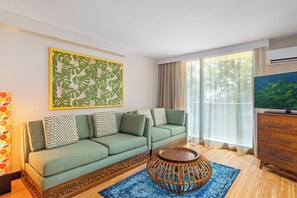 Un salon avec un canapé vert, un tapis bleu à motifs et une table basse en bois.