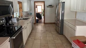 A kitchen with white cabinets, a stainless steel refrigerator, a microwave, and a coffee maker.