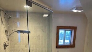 A bathroom with a glass-enclosed shower, a toilet, and a sink with a granite countertop.