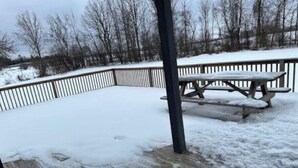 A wooden deck with a picnic table and a metal railing.