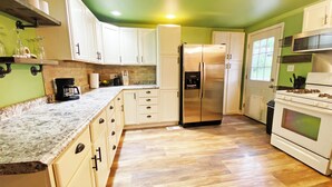 A kitchen with white cabinets, a stainless steel refrigerator, a stove, and a microwave. - Cozy home in St. Joseph, MO that is centrally located to hospital & university! (Saint Joseph)