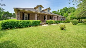 A two-story brick house with a front porch, surrounded by well-maintained lawns and hedges. - Perry Family Home on 2 Acres w/ Private Pool (Perry)