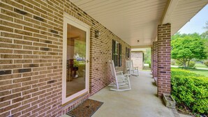 A covered porch with a brick exterior, a sliding glass door, and a doormat. - Perry Family Home on 2 Acres w/ Private Pool (Perry)