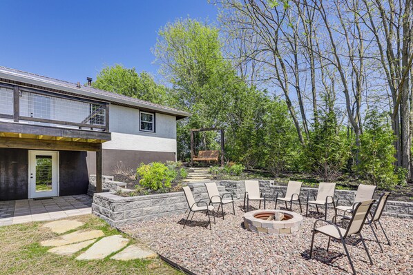 A patio with outdoor seating and a fire pit, surrounded by a stone wall and greenery. - Dry Ridge Farmhouse w/ Hot Tub + Game Room! (Dry Ridge)