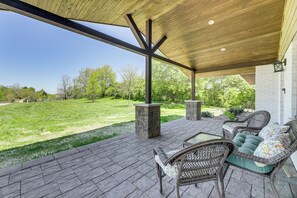 An outdoor patio with wicker furniture and a view of a grassy area. - Dry Ridge Farmhouse w/ Hot Tub + Game Room! (Dry Ridge)