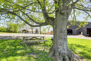 A picnic table and a large tree in a grassy area with a barn in the background. - Dry Ridge Farmhouse w/ Hot Tub + Game Room! (Dry Ridge)