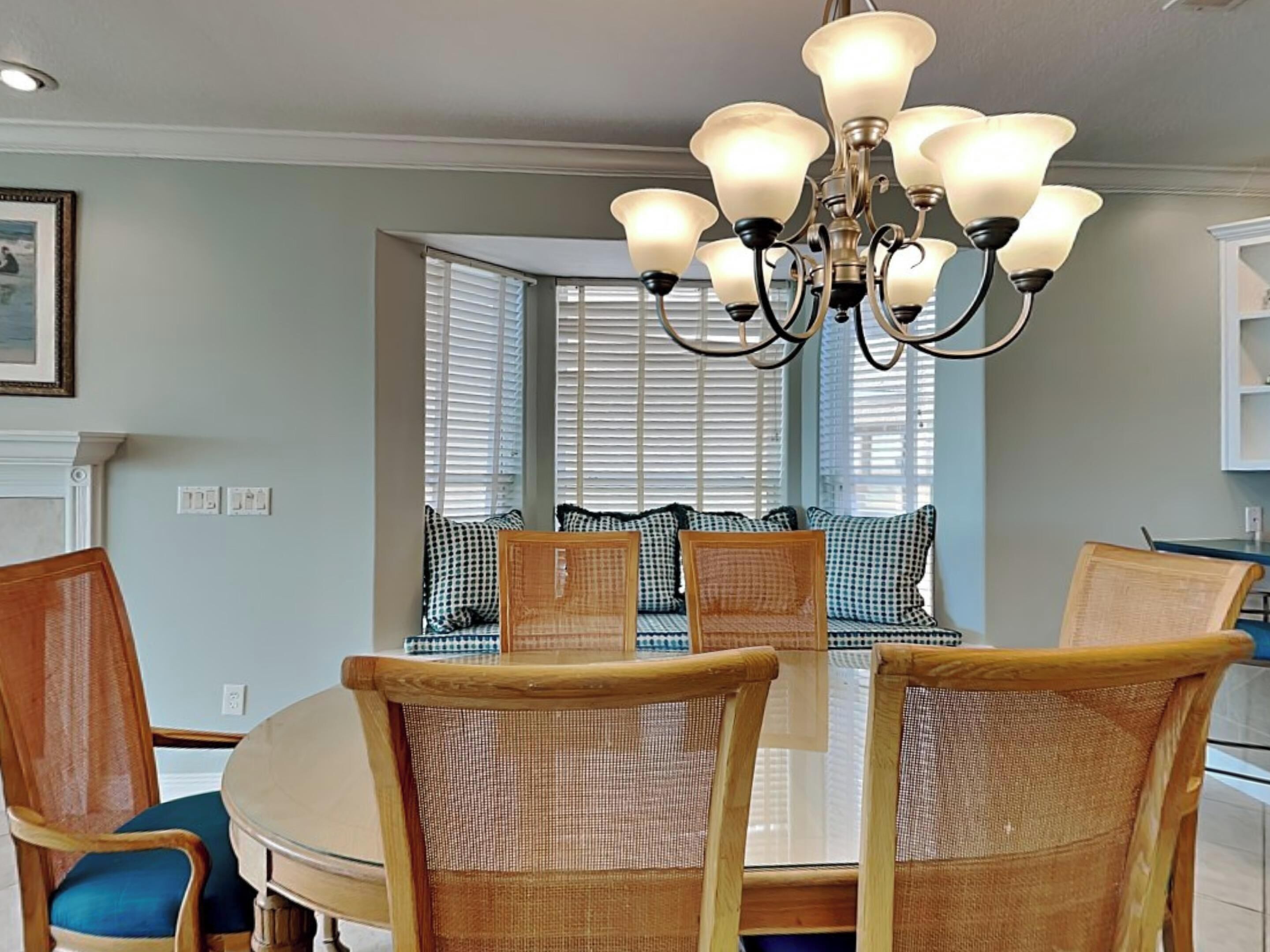 Un coin repas avec une table ronde, des chaises en osier et un lustre.