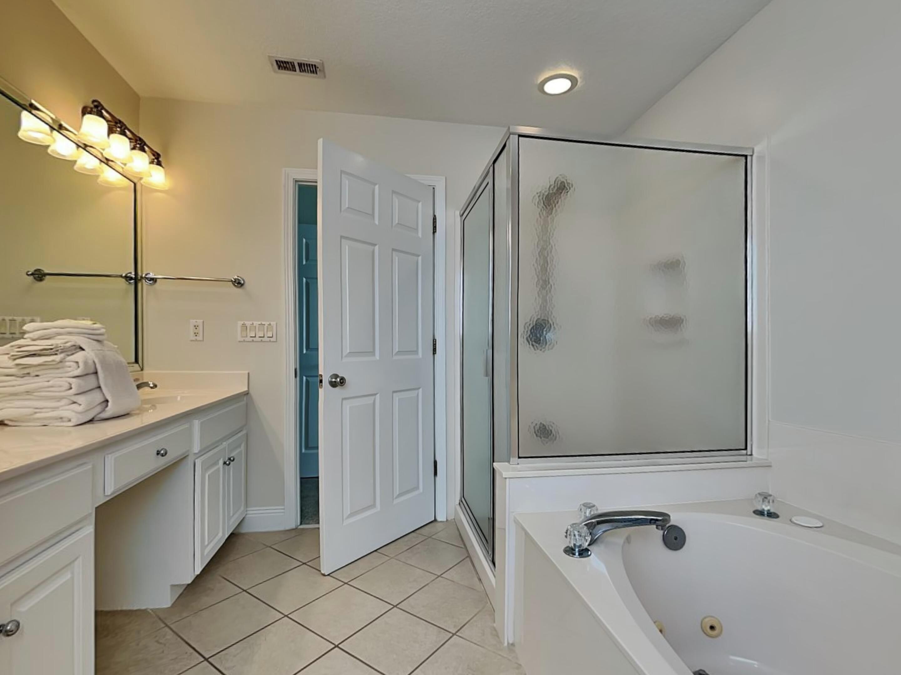A modern bathroom with a white vanity, a glass-enclosed shower, and a bathtub.