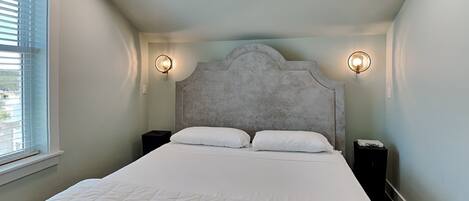 Une chambre à coucher avec un grand lit, deux tables de chevet et deux lampes fixées au mur.