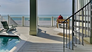 A wooden deck with a pool, a barbecue grill, and a view of the beach. - Breezy Beach by Resort Collection (Panama City Beach)