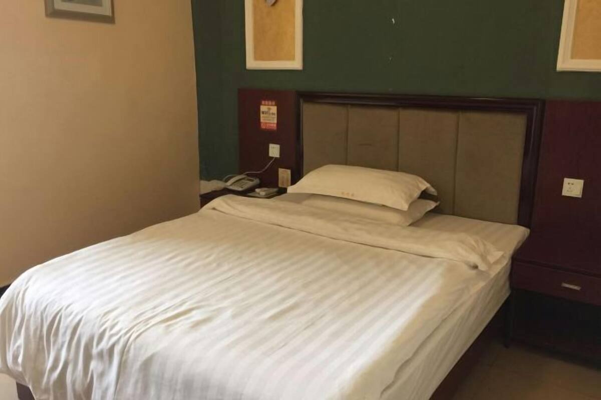 A hotel room with a bed, a nightstand, and a telephone.