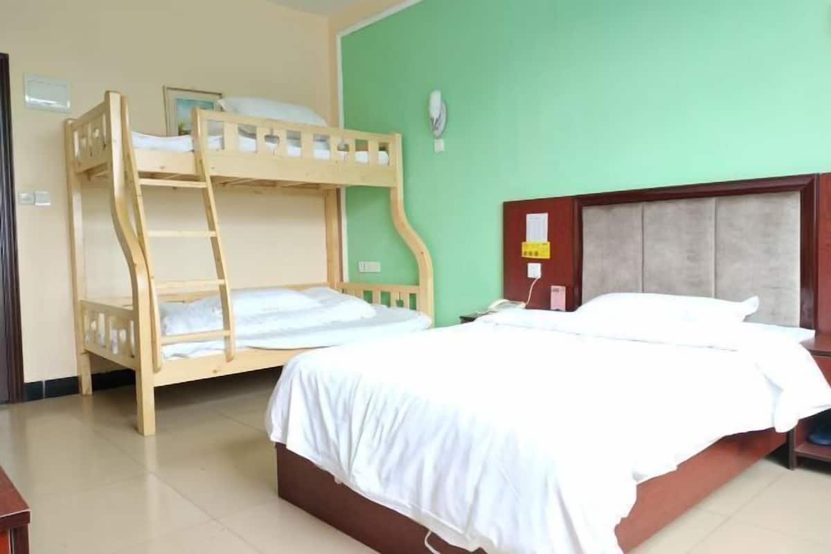 A room with a bunk bed and a single bed, both with white bedding.