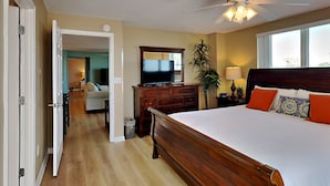 A hotel room with a large bed, a television, a ceiling fan, a window, and a view of the outside. - Dune Point #303 by Southern Vacation Rentals (Fort Walton Beach)