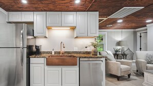 A modern kitchen with white cabinets, stainless steel appliances, and a central island. - Collins River Cottage (Warren County)