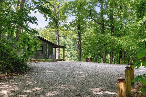A gravel driveway leading to a wooden cabin surrounded by dense trees. - Collins River Cottage (Warren County)