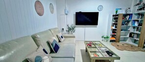 A living room with a sofa, a coffee table, a TV, a bookshelf, and a clock on the wall.