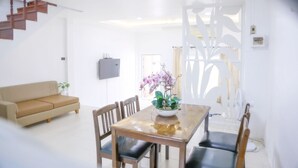 Un salon moderne avec une table à manger en bois, des chaises, un canapé et une plante décorative.